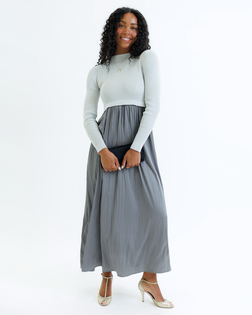 Woman wearing a gray dress with long sleeves and a mockneck on a white background