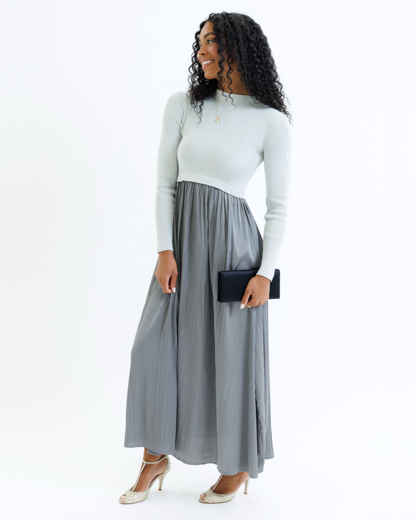 Woman wearing a gray dress with long sleeves and a mockneck on a white background