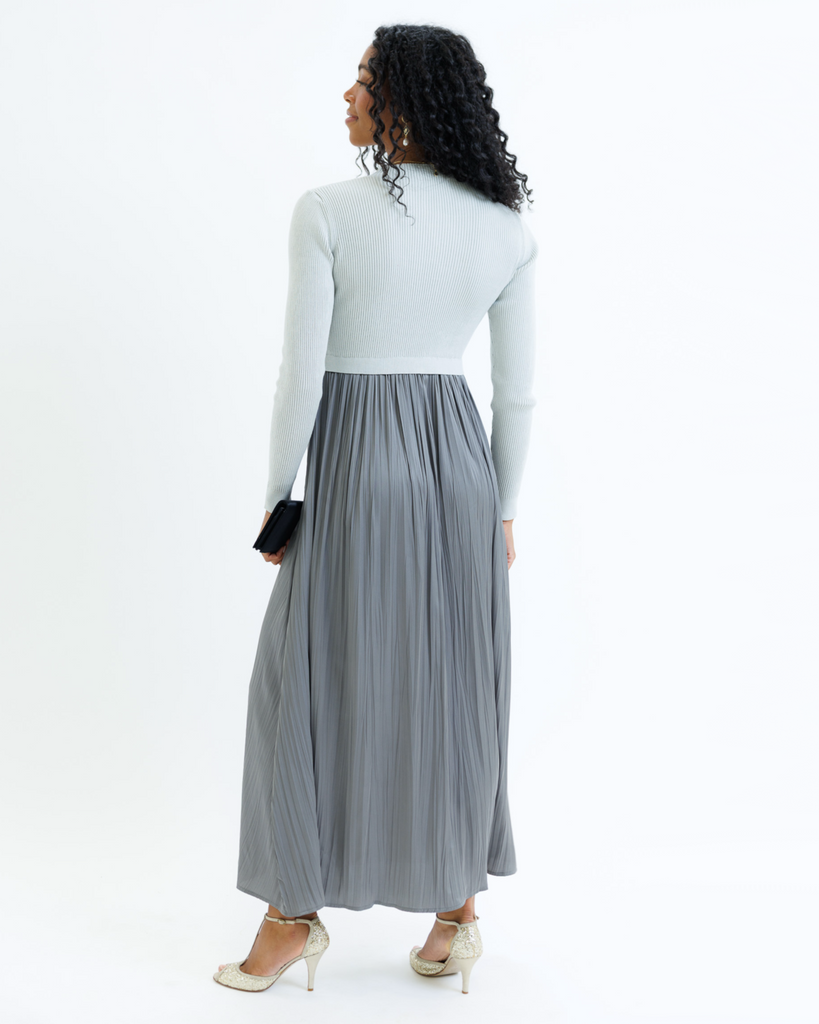 Woman wearing a gray dress with long sleeves and a mockneck on a white background