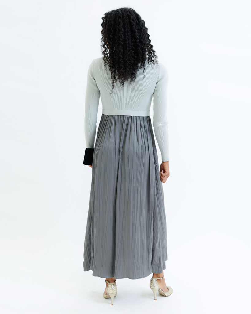 Woman wearing a gray dress with long sleeves and a mockneck on a white background