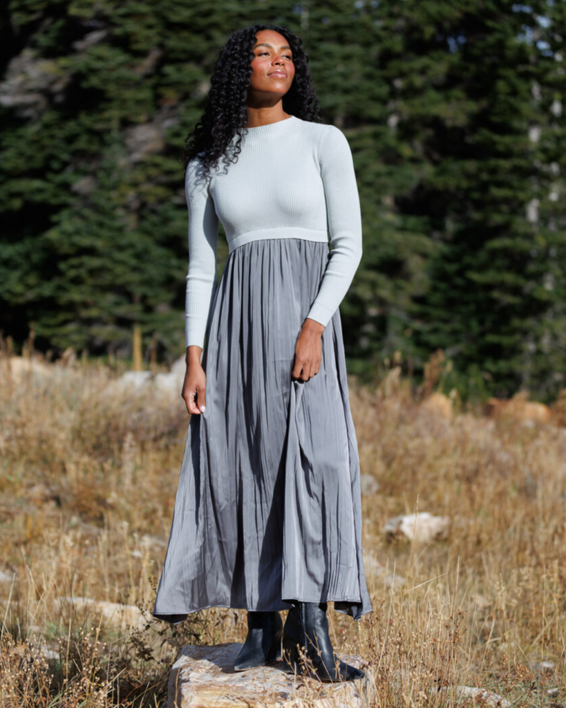 Woman wearing a gray dress with long sleeves and a mockneck in the outdoors
