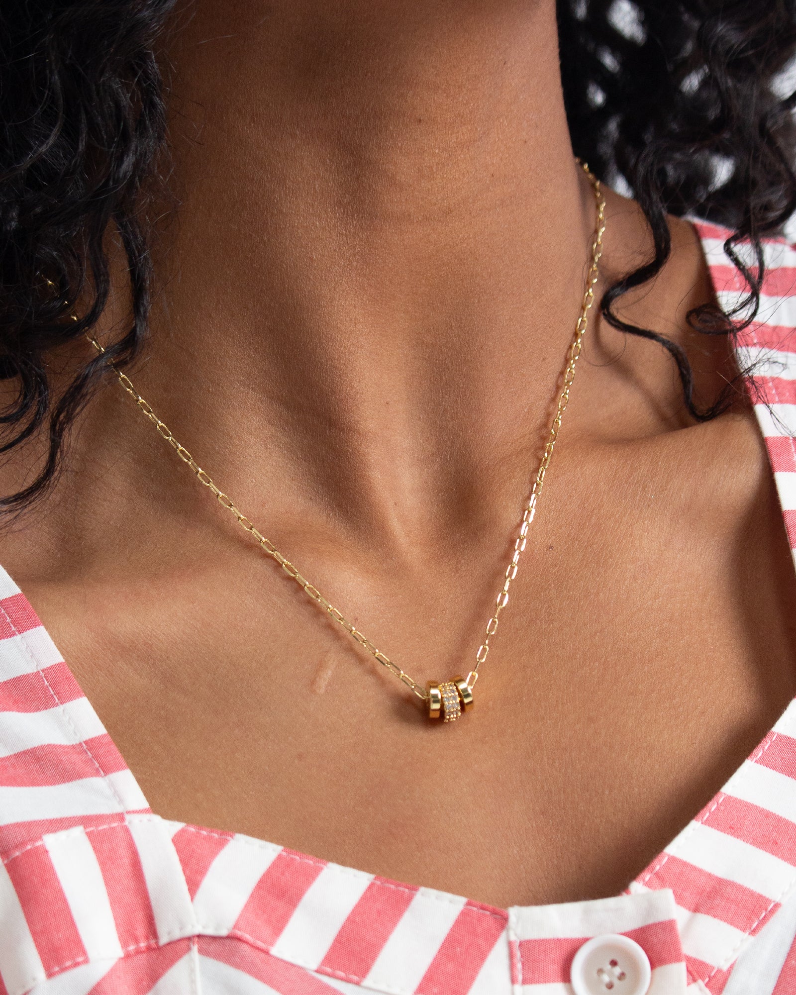 Gold necklace on a person wearing a red and white striped shirt