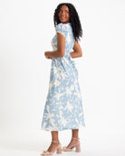 Woman wearing a light blue dress with white floral pattern on a white background