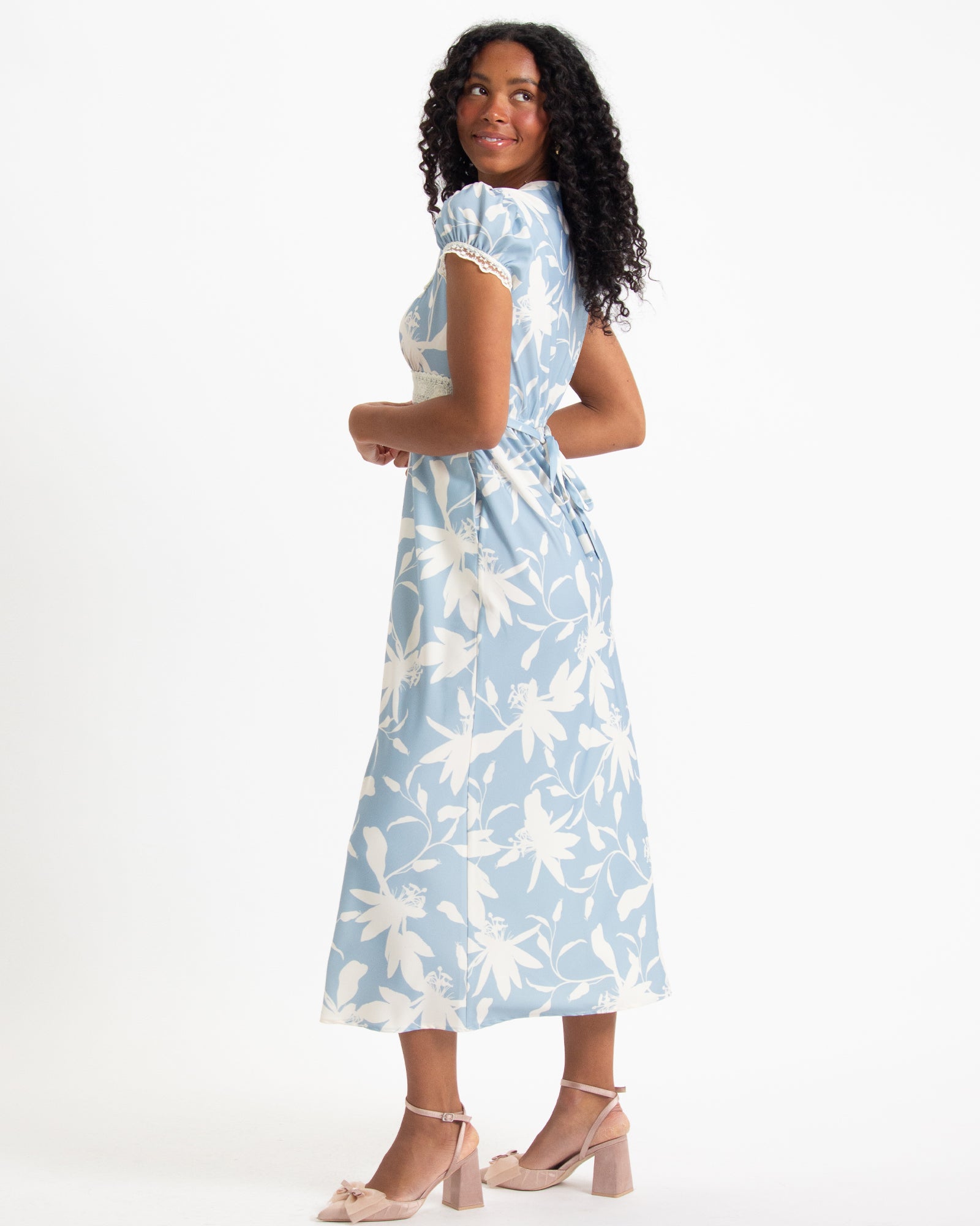 Woman wearing a light blue dress with white floral pattern on a white background