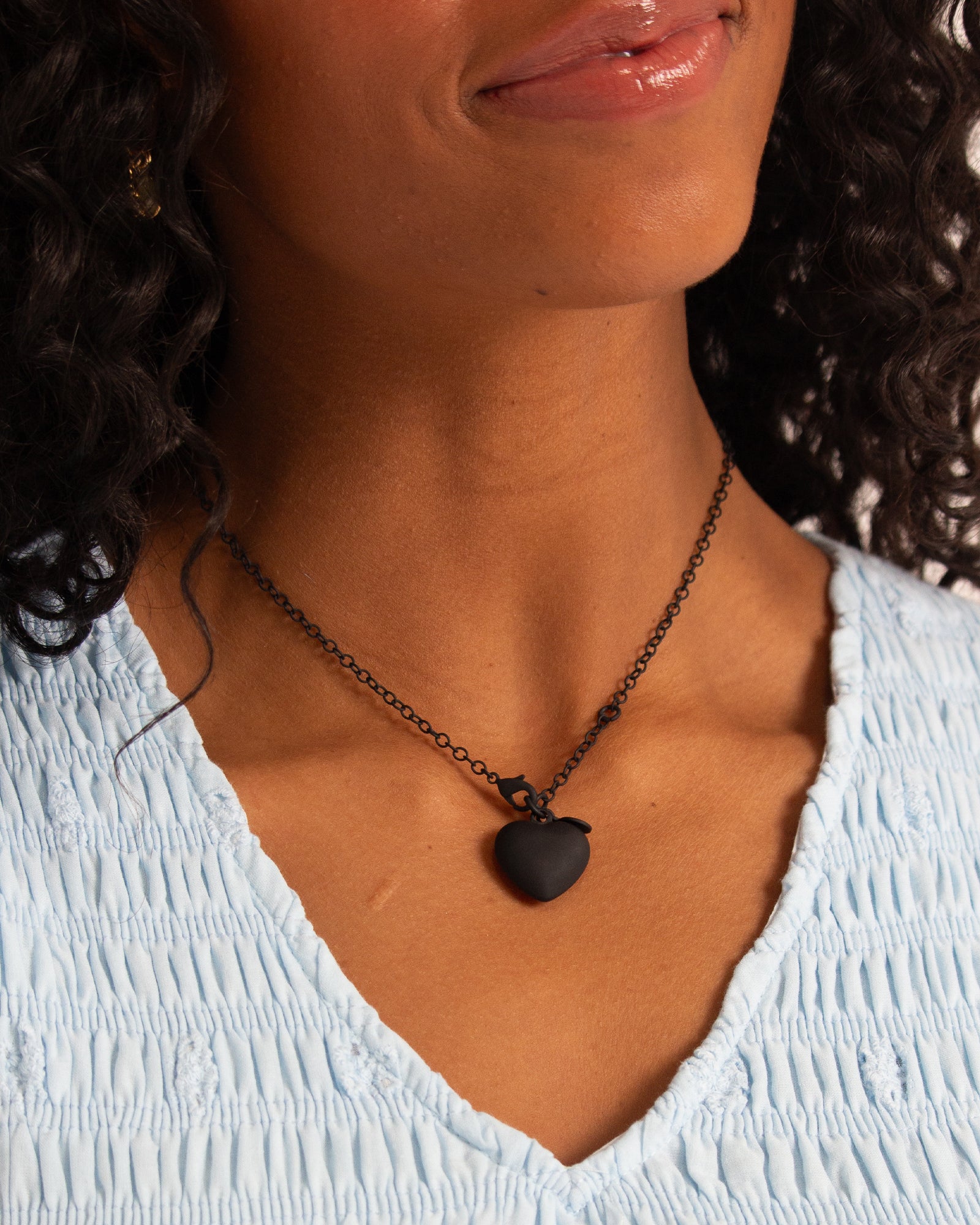 Close-up of a person wearing a necklace with a heart pendant.