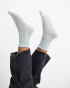White socks with black polka dots worn with dark jeans on a white background