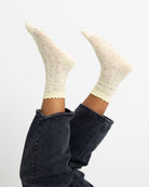 White socks with black polka dots worn with dark jeans on a light gray background