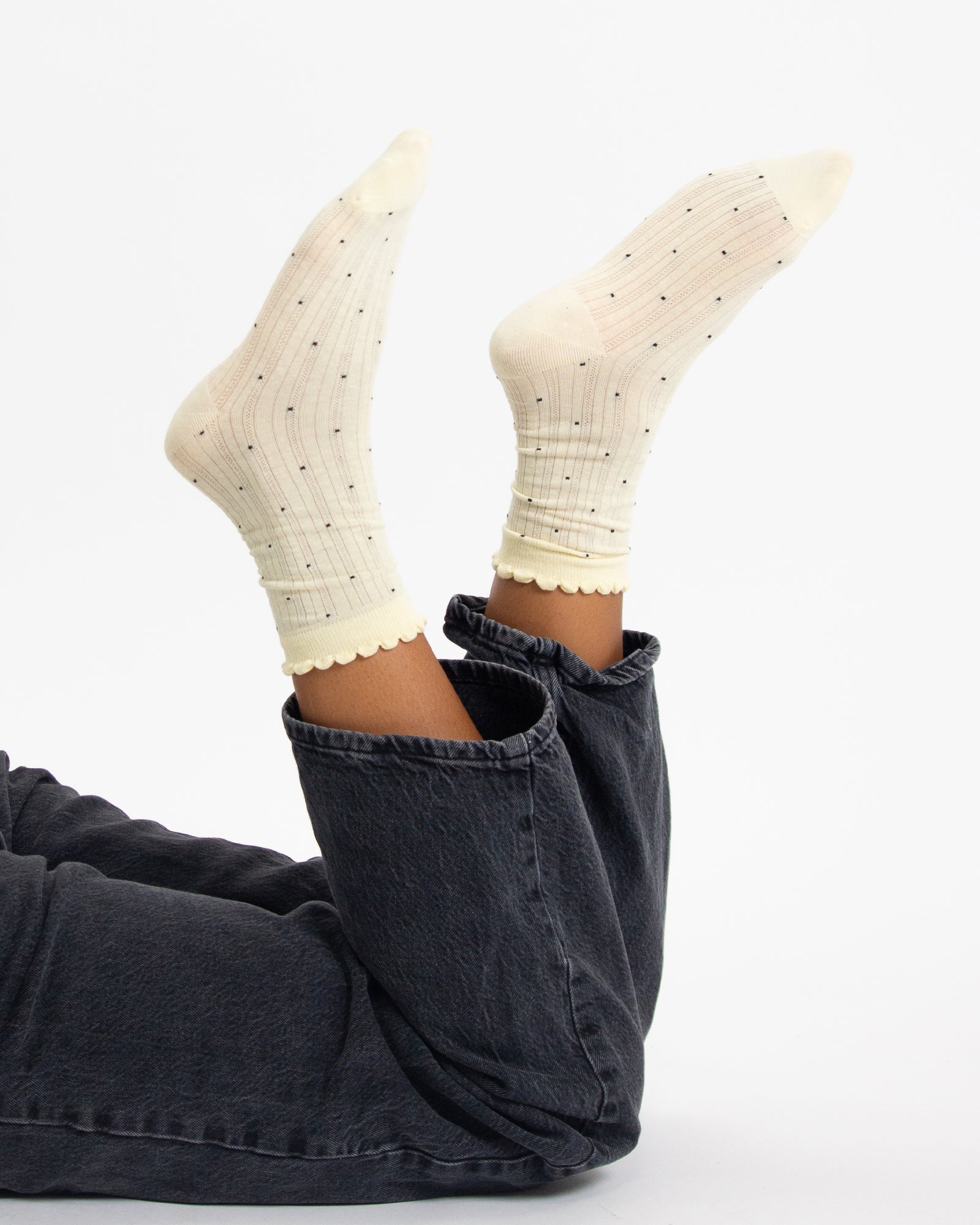 White polka dot socks worn with dark jeans on a white background