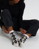 Person wearing black and white patterned socks on a plain background