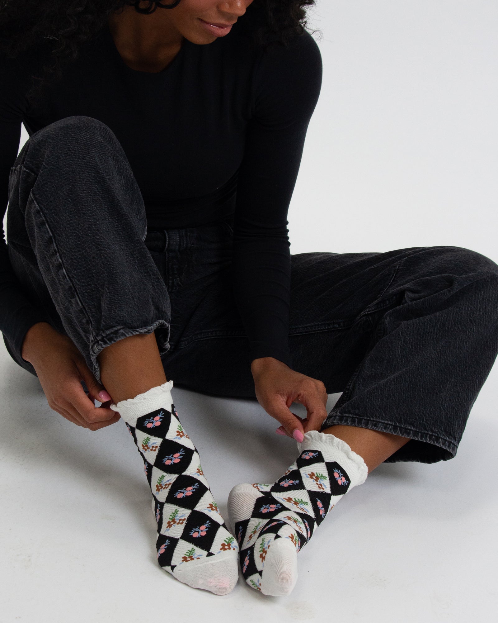 Person wearing black and white patterned socks on a plain background