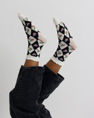 Checkered socks with floral patterns worn by a person on a light gray background
