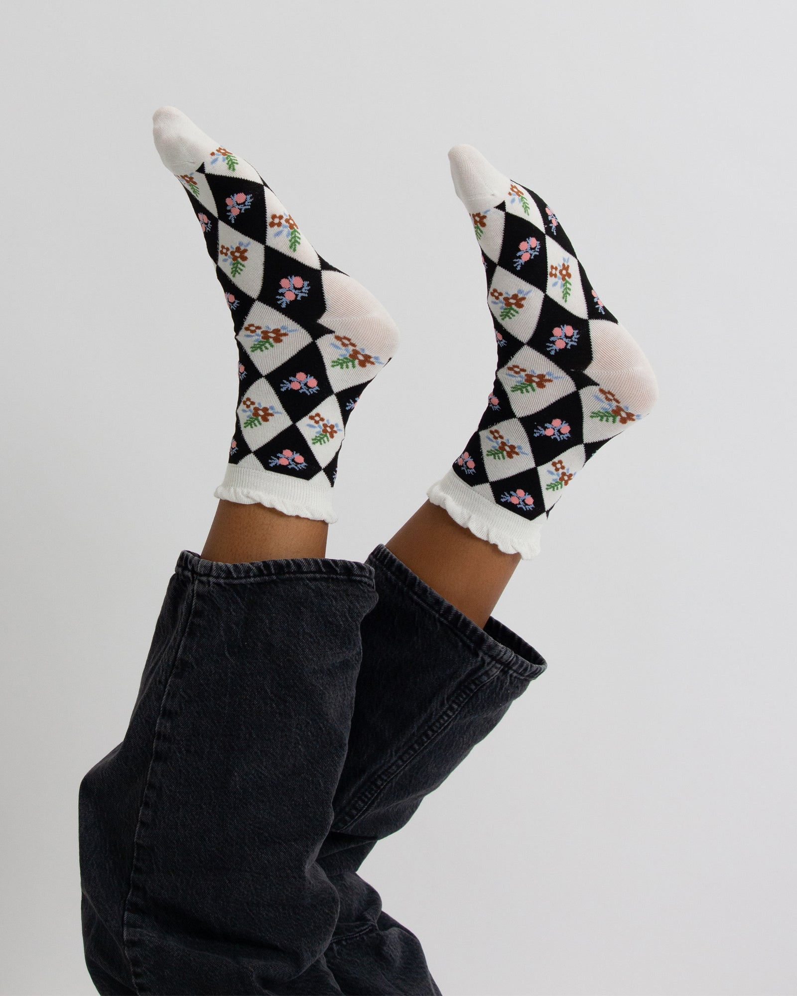 Checkered socks with floral patterns worn by a person on a light gray background