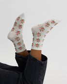 White socks with floral pattern worn by a person on a light gray background