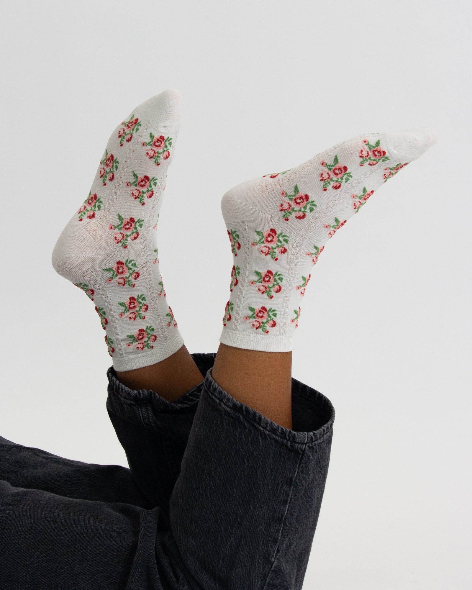 White socks with floral pattern worn by a person on a light gray background