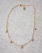 Gold necklace with small charms on a textured gray background