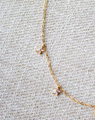 Delicate gold necklace with small pendants on a textured beige fabric background
