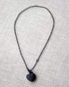 Black heart pendant necklace on a textured gray background