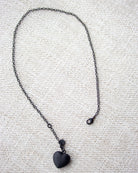 Black heart pendant necklace on a textured fabric background