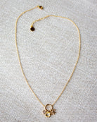 Gold necklace with a floral pendant on a gray textured background