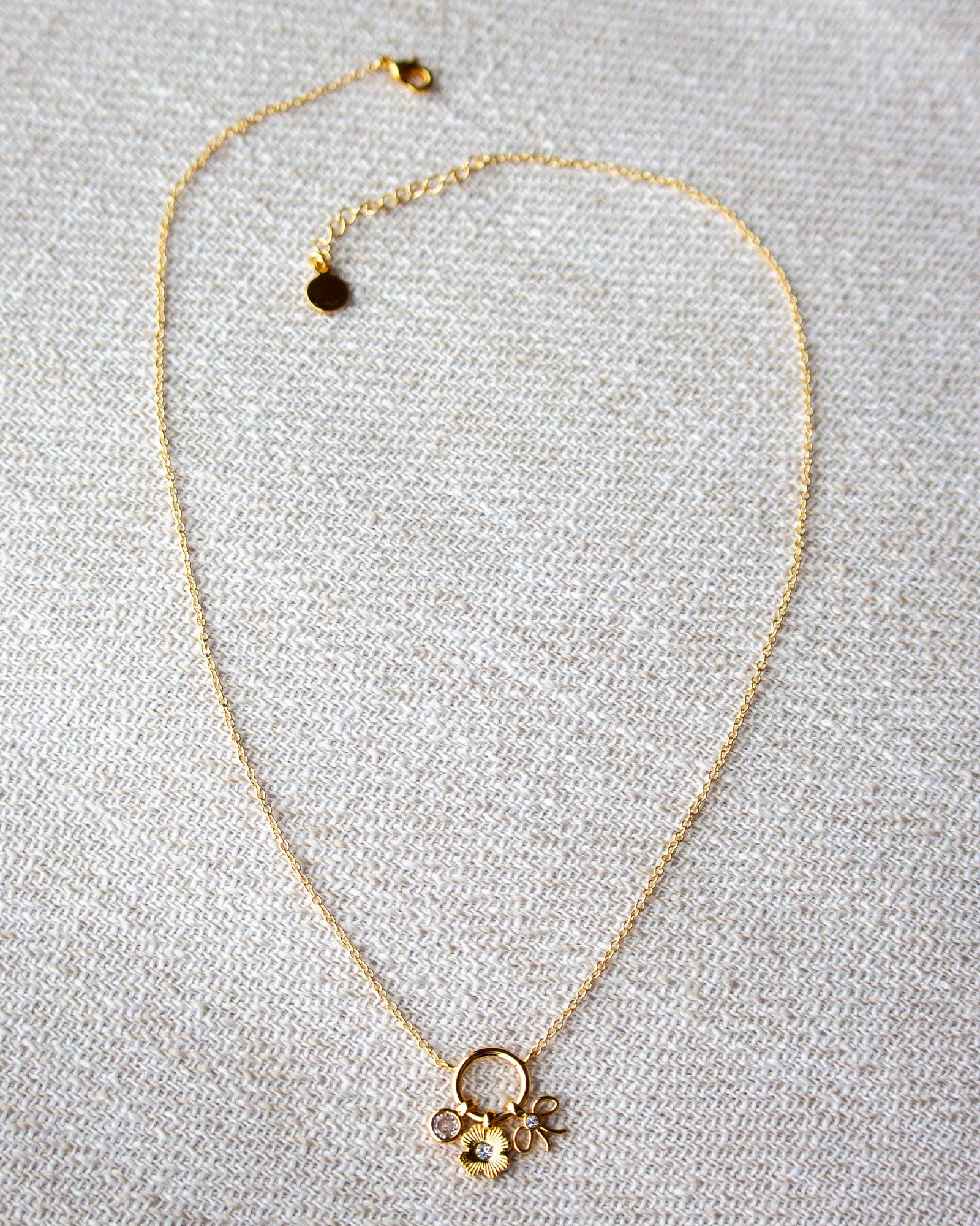 Gold necklace with a floral pendant on a gray textured background