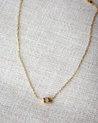 Gold necklace with a small pendant on a textured gray surface