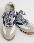 Beige sneakers with navy and white checkered laces on a white background