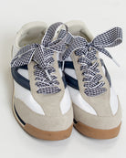 Pair of white sneakers with gingham checkered laces on a white background