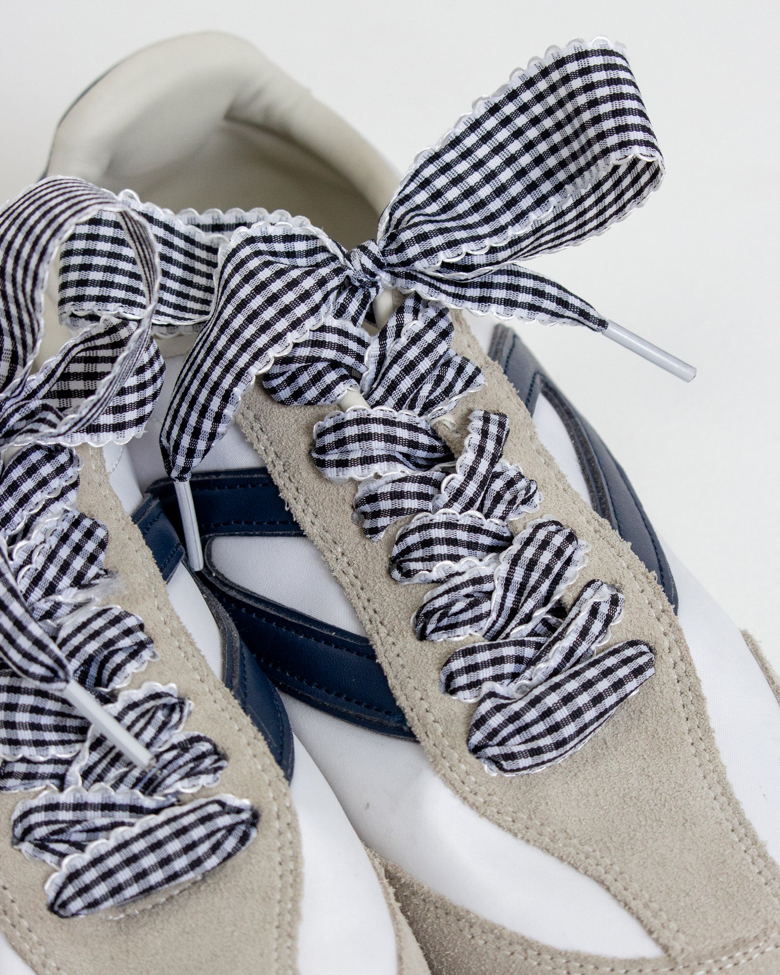 Pair of shoes with gingham ribbon details on a white background