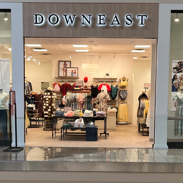 Storefront of a clothing store named 'DOWN EAST' with interior display.