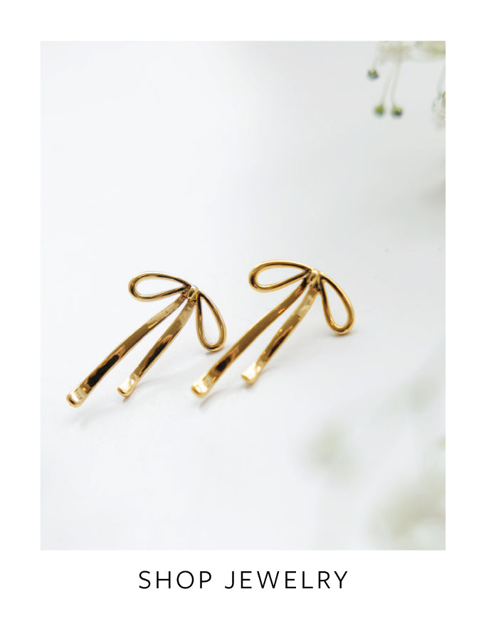 Gold bow-shaped earrings on a light background with 'Shop Jewelry' text.