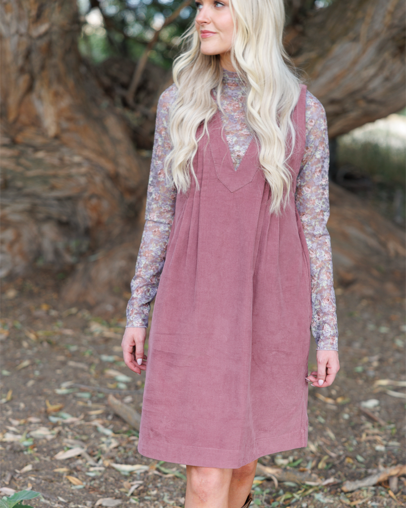 Woman wearing a floral long sleeve underneath a dress standing outside.