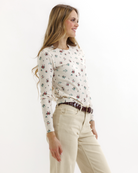 Woman wearing a floral top and beige pants on a white background
