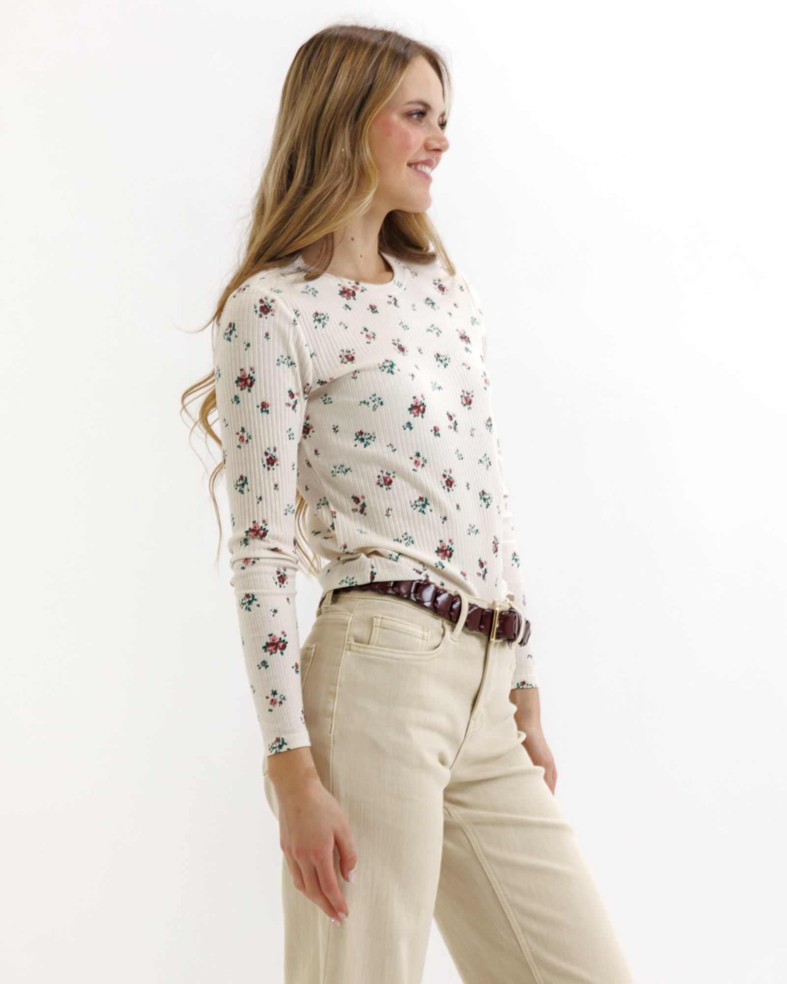 Woman wearing a floral top and beige pants on a white background