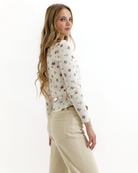 Woman wearing a floral top and beige pants on a white background