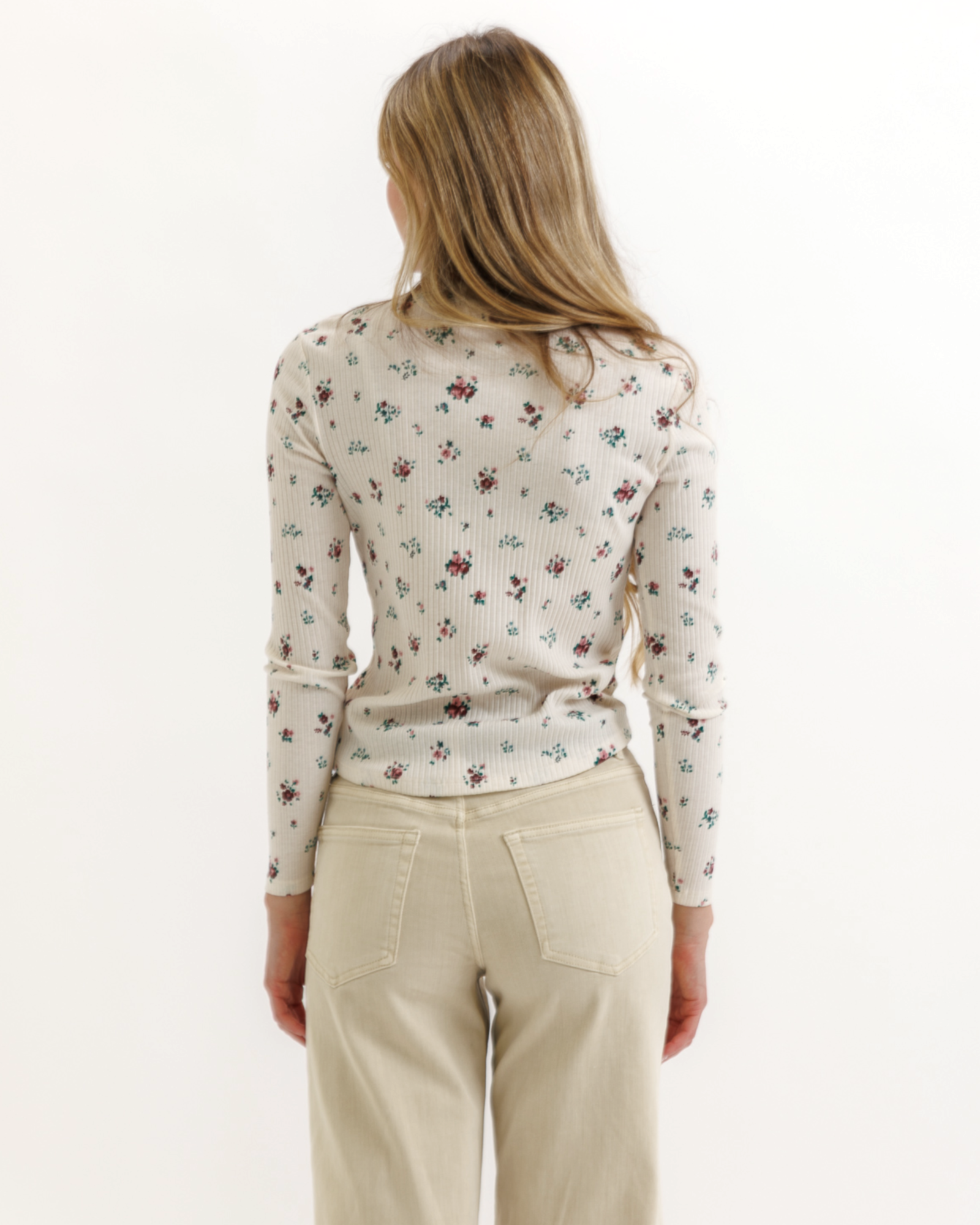 Woman wearing a floral top and beige pants on a white background
