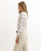 Woman wearing a floral top and beige pants on a white background