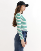Woman wearing a green and white striped long-sleeve shirt and blue jeans on a white background