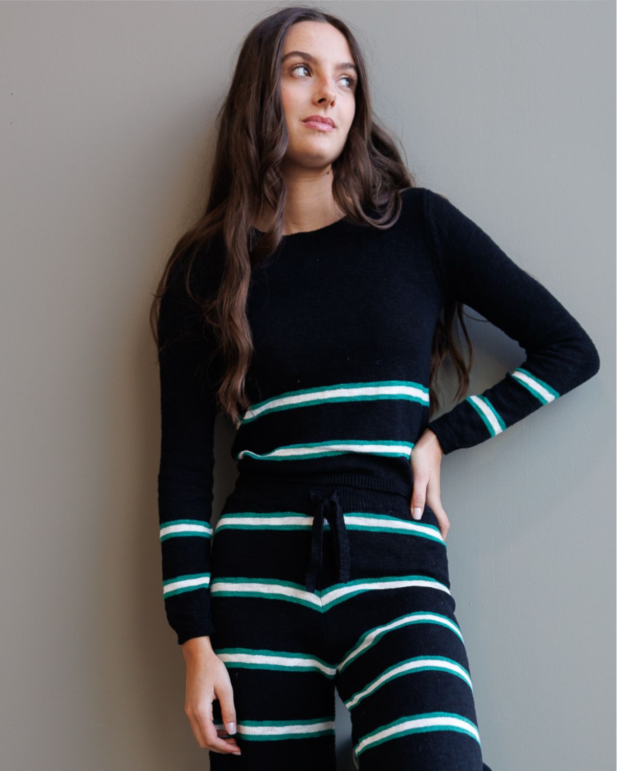Woman wearing a black and green striped outfit against a plain background