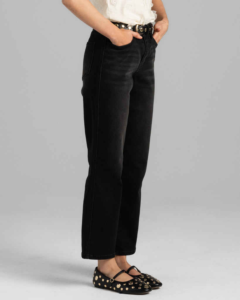 Model wearing a black pair of bootcut, ankle length denim pants.