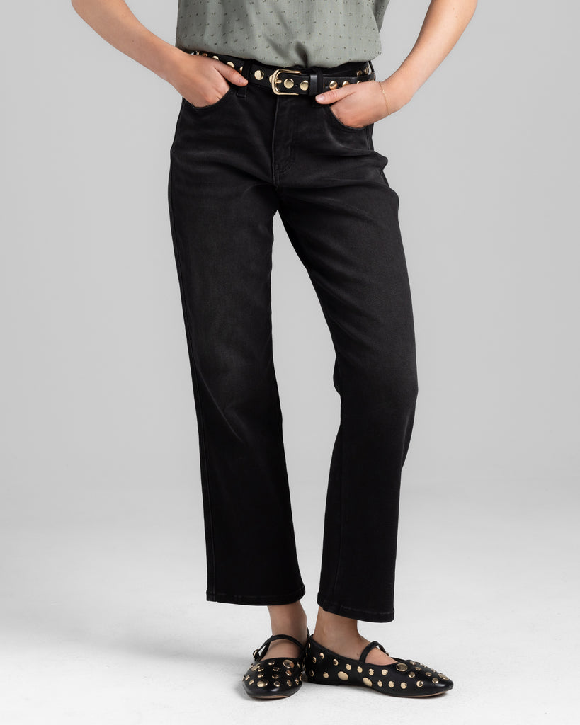 Model wearing a black pair of bootcut, ankle length denim pants.