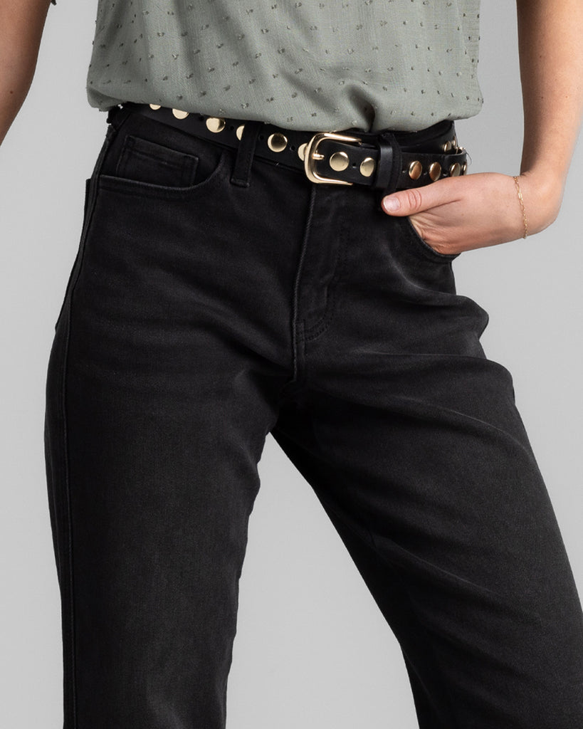 Model wearing a black pair of bootcut, ankle length denim pants.