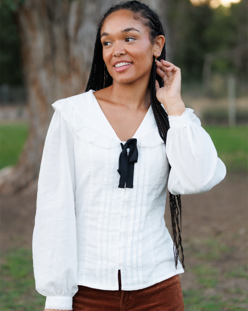 Woman wearing a white blouse with a black bow tie outdoors