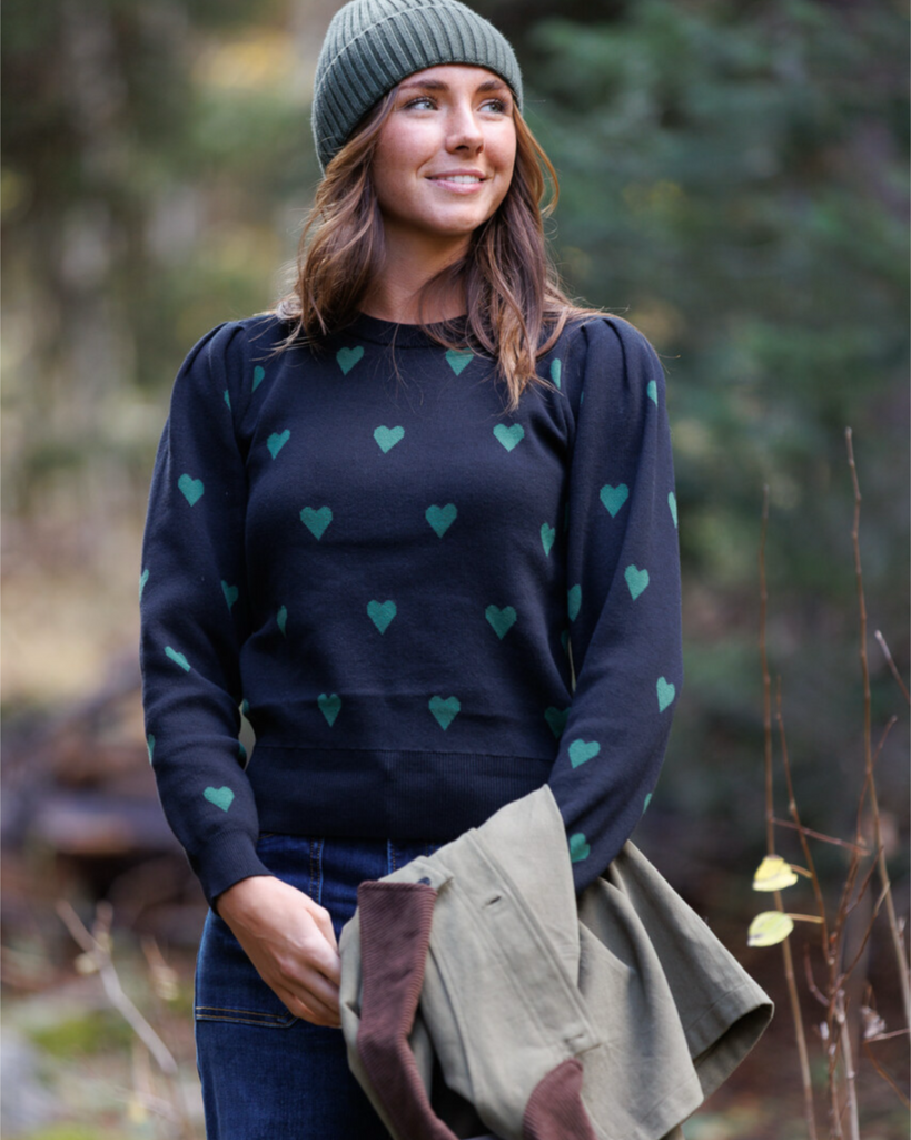 Woman wearing a black sweater with green heart patterns in the outdoors