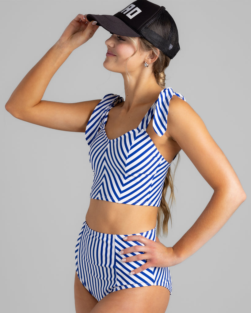 Model wearing a white and blue chevron striped tankini top with matching high-waisted swim bottoms.