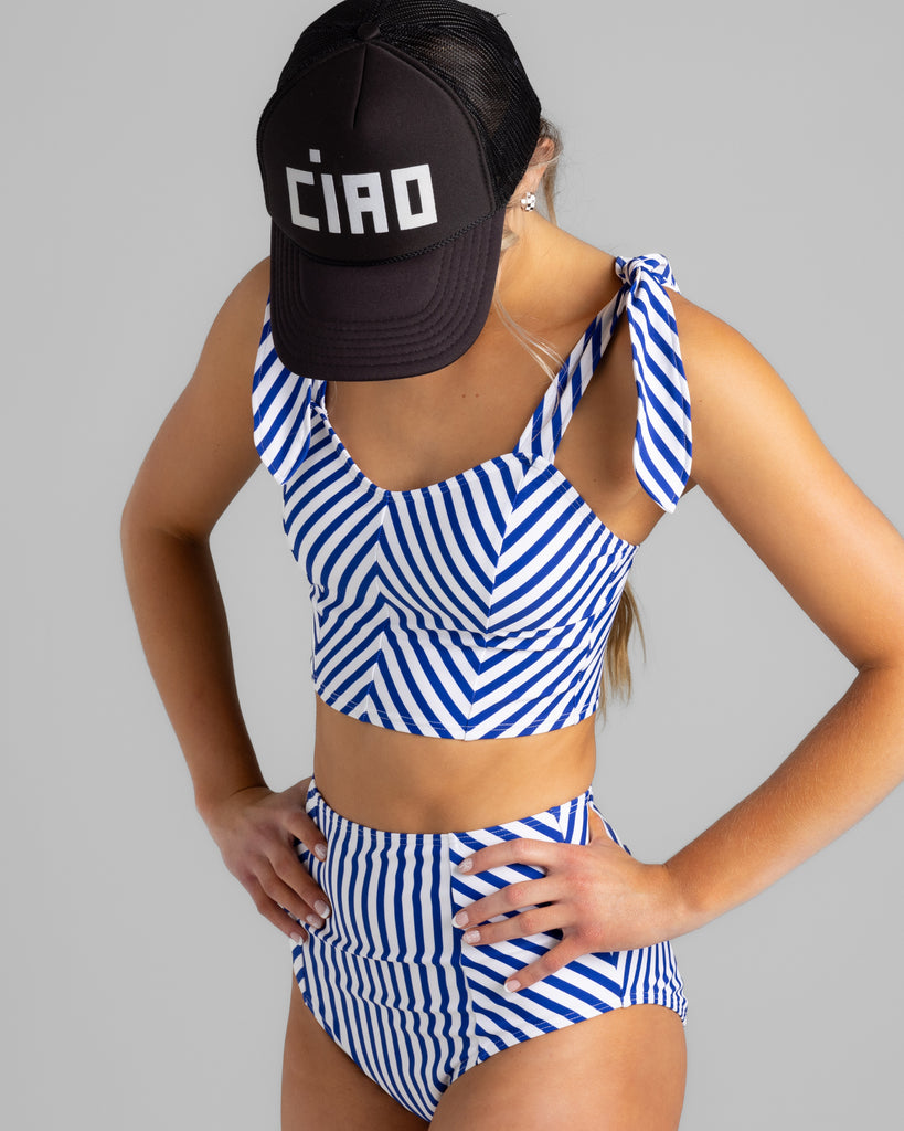 Model wearing a blue and white chevron striped tankini with matching swim bottoms.