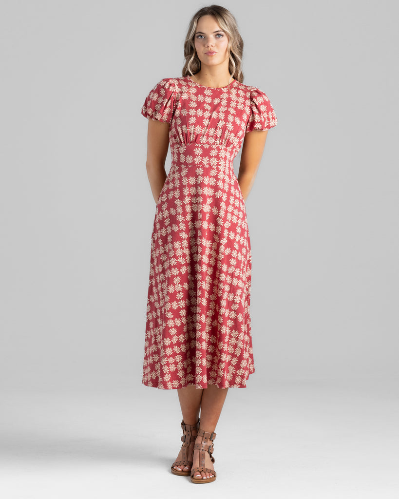 Model wearing a red with white daisy print, short sleeve midi length knit dress.