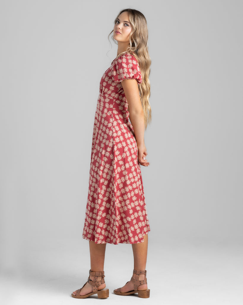 Model wearing a red with white daisy print, short sleeve midi length knit dress.