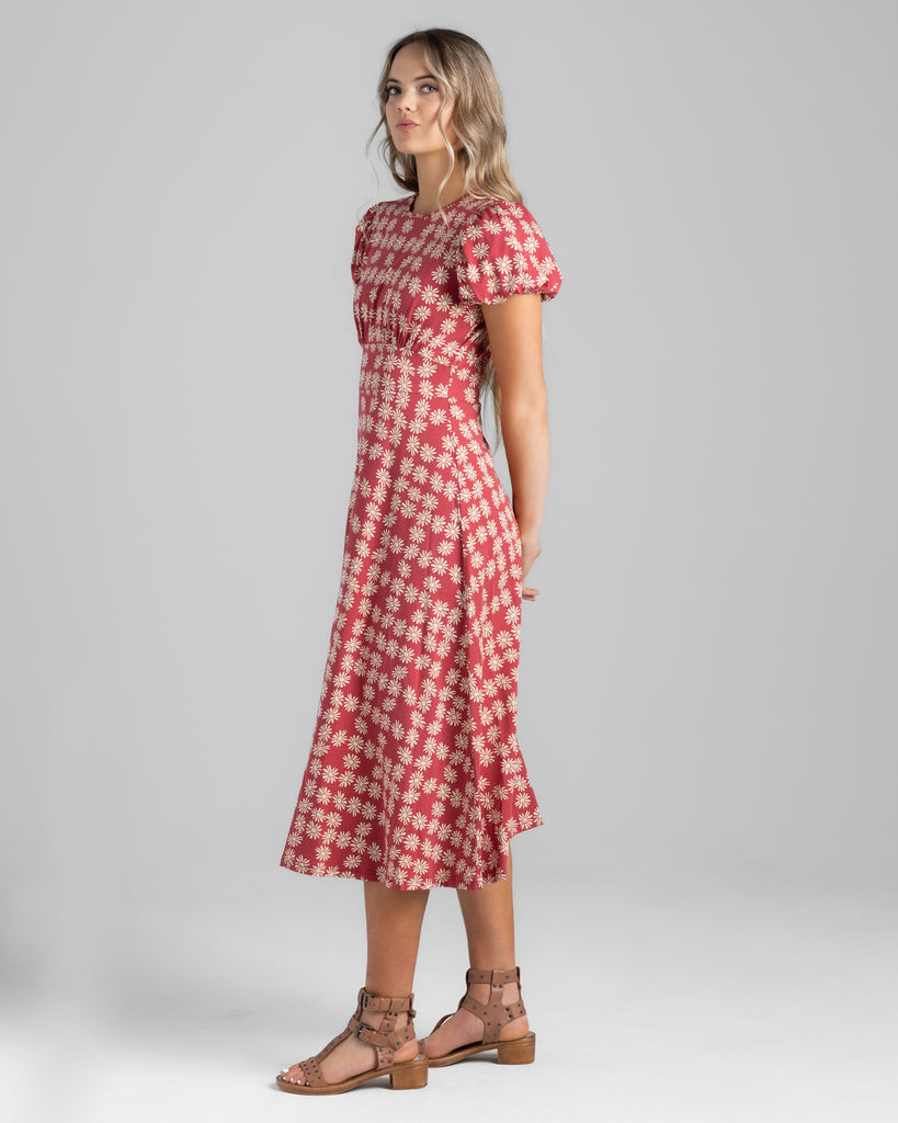 Model wearing a red with white daisy print, short sleeve midi length knit dress.