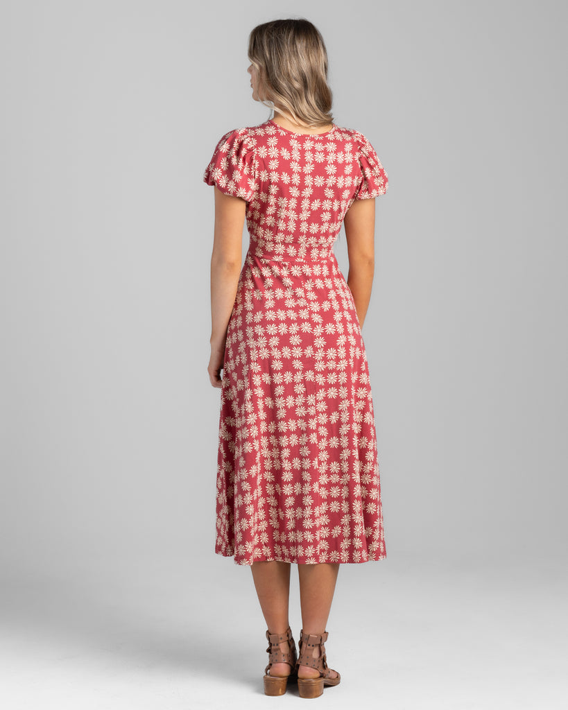 Model wearing a red with white daisy print, short sleeve midi length knit dress.