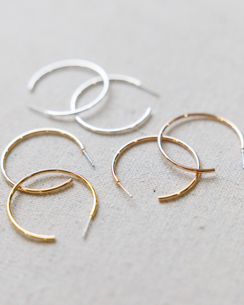 Gold and silver hoop earrings on a beige background